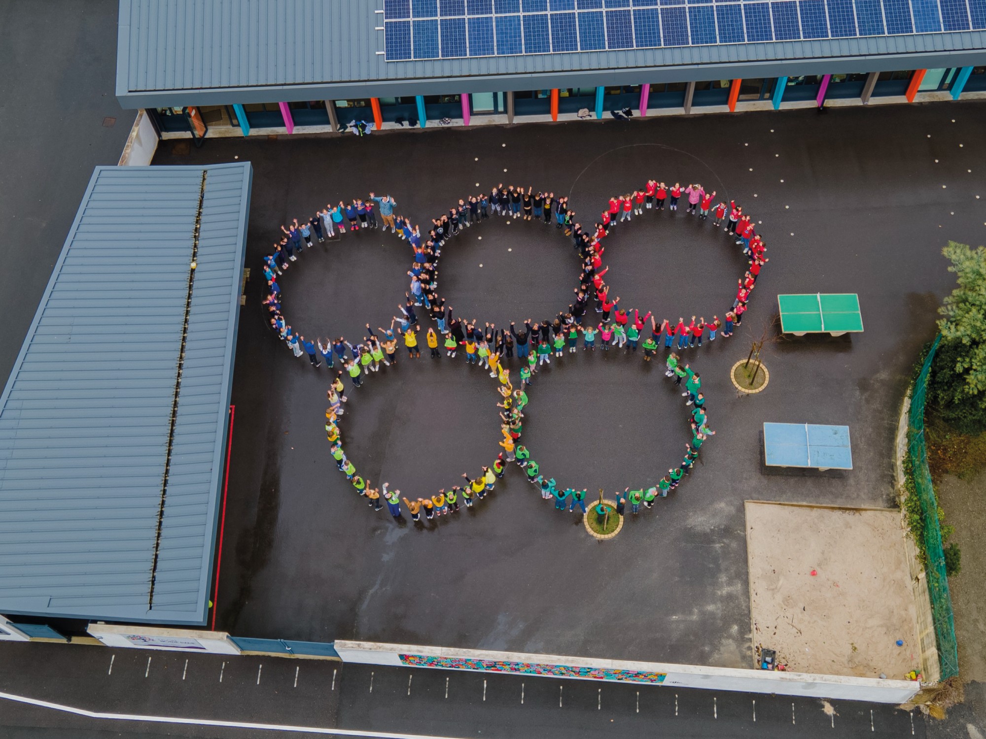 Photographie drone d'un événement scolaire, enfants faisant le symbole olympique