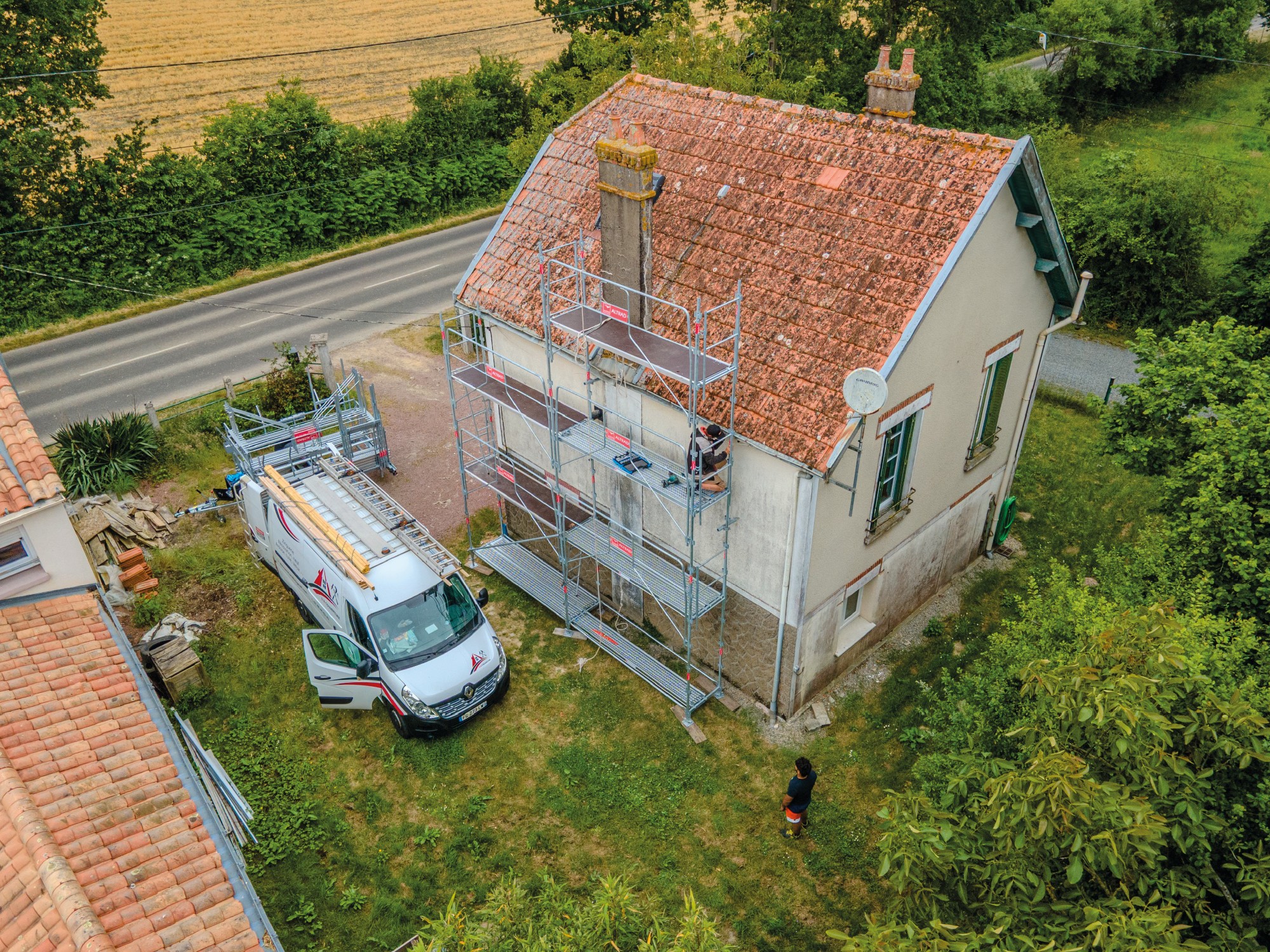 Photographie par drone d'un couvreur établissant un échafaudage de sécurité en vue d'un chantier de rénovation de toiture