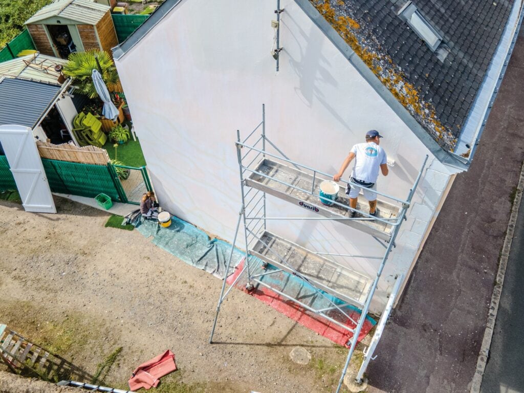 Photo drone d'une entreprise de peinture en plein ravalement de façade sur une maison.