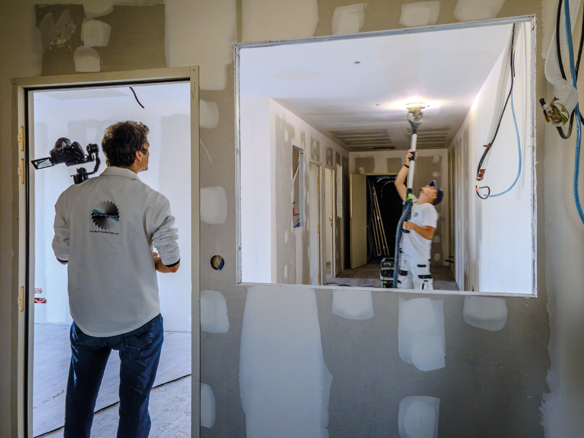 Photographie de Matthieu DronEsprit, caméra à la main, entrain de filmer une entreprise de peinture sur un chantier.
