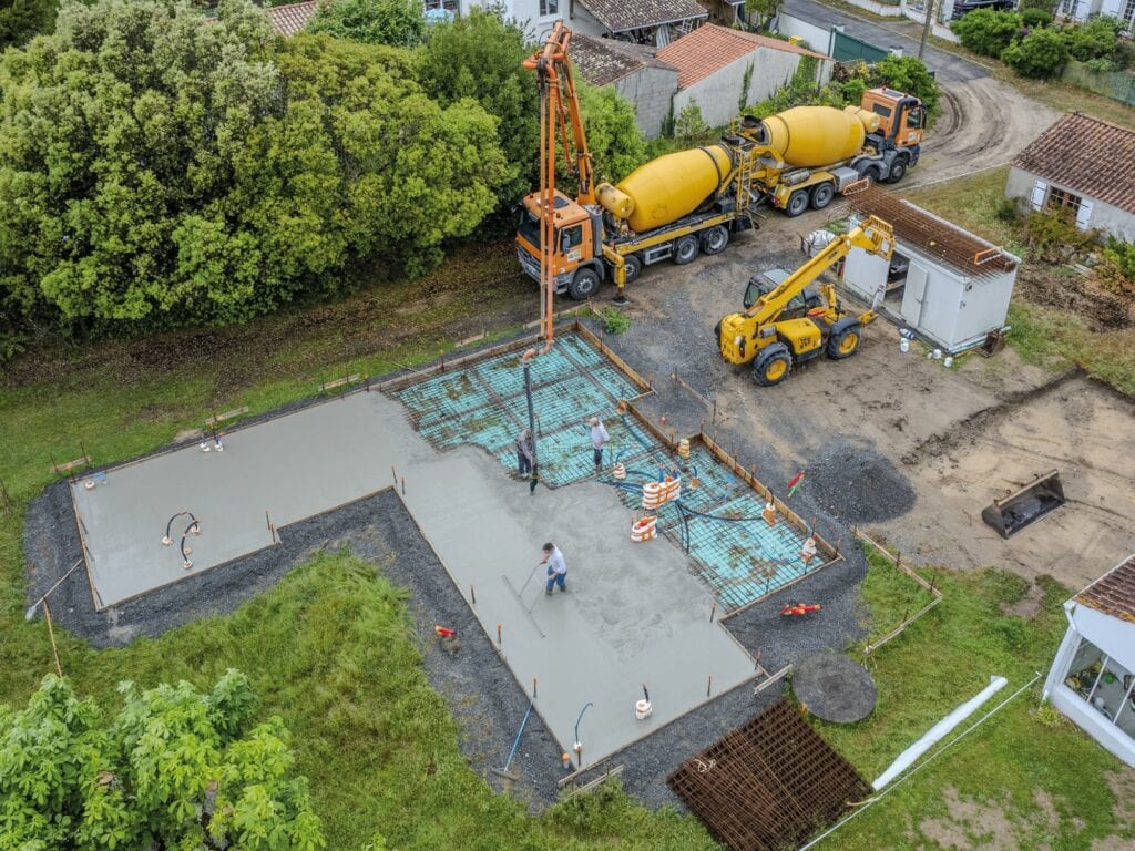 Photographie aérienne par drone de la construction d'une maison à l'étape du coulage de la dalle.