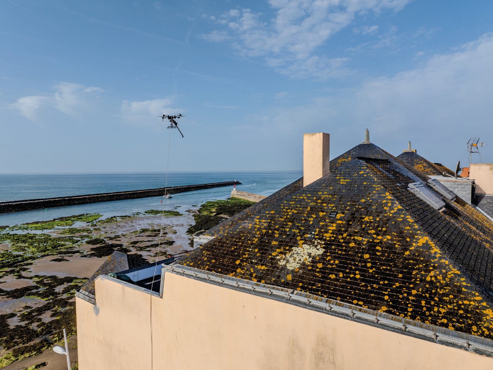 Vue aérienne d'un drone de pulvérisation entrain de nettoyer la toiture d'une copropriété à Saint Gilles Croix de Vie en Vendée.