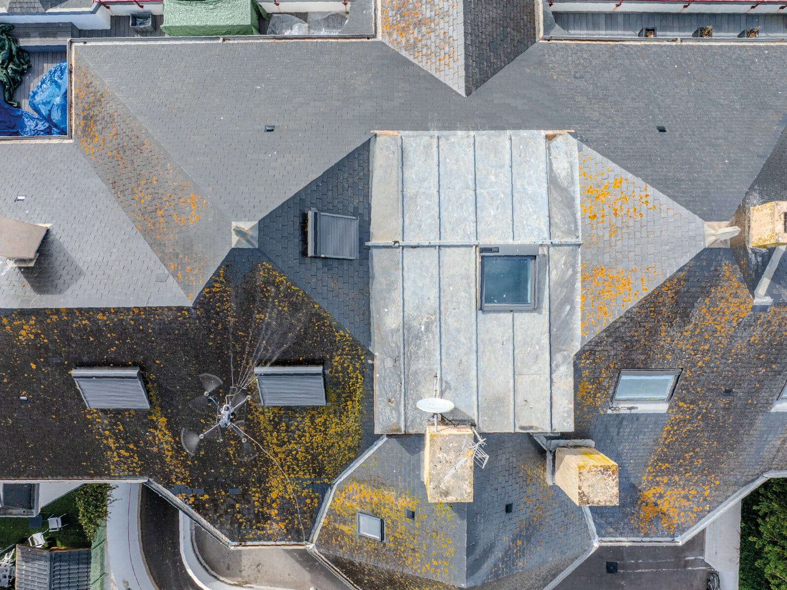 Photographie nadirale d'un drone de pulvérisation entrain de nettoyer la toiture ardoise d'une copropriété sur la corniche de Saint Gilles Croix de Vie.