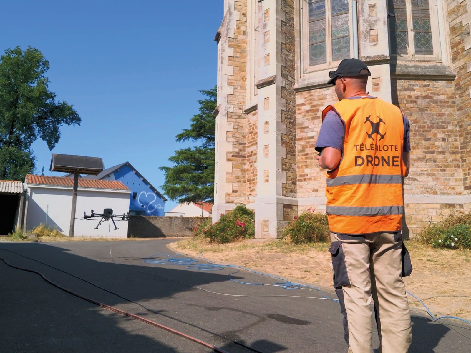 Photographie d'Antoine Mignot d'AM Drone, entrain de poser son drone de pulvérisation pendant le chantier de nettoyage d'une église.